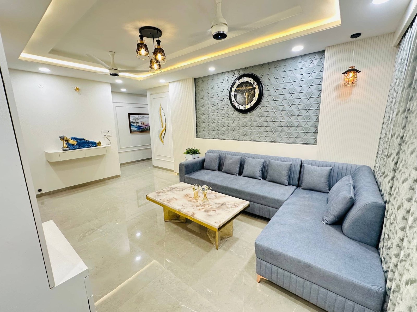 Living room with a grey L-shaped sofa, marble-top coffee table and cove lighting