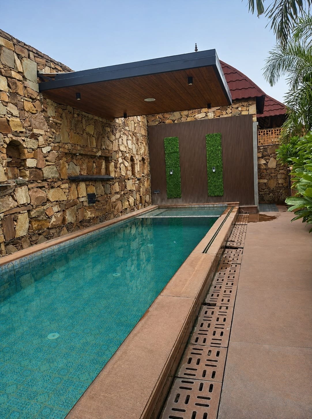 Long pool beside a stone wall, with a covered deck at one end