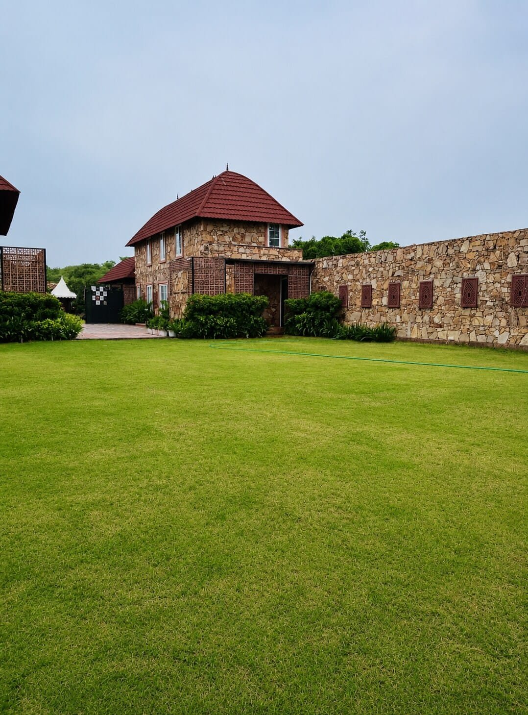 Open lawn in front of a stone building with a red tiled roof
