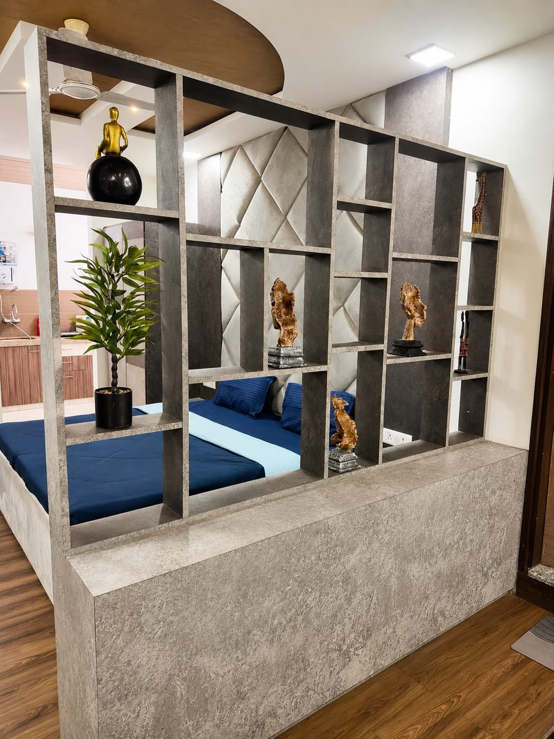 Open shelf divider with decor beside the bed with a navy cover
