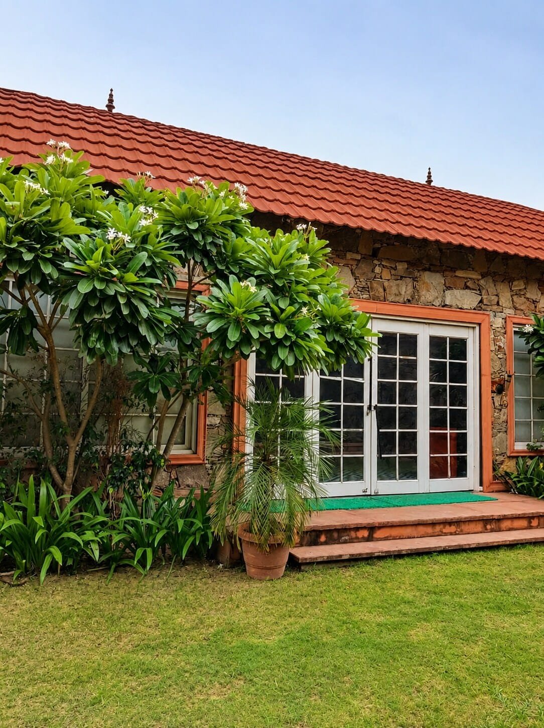 Stone cottage with a red tiled roof and French windows opening onto a lawn