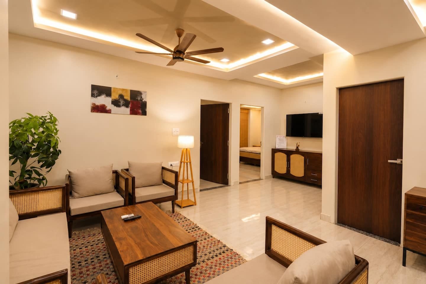 Open living area with cane seating, a TV console and doors to the bedrooms