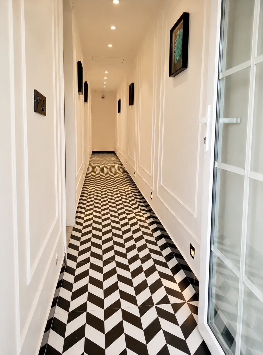 Hallway with a black-and-white chevron floor and white panelled walls
