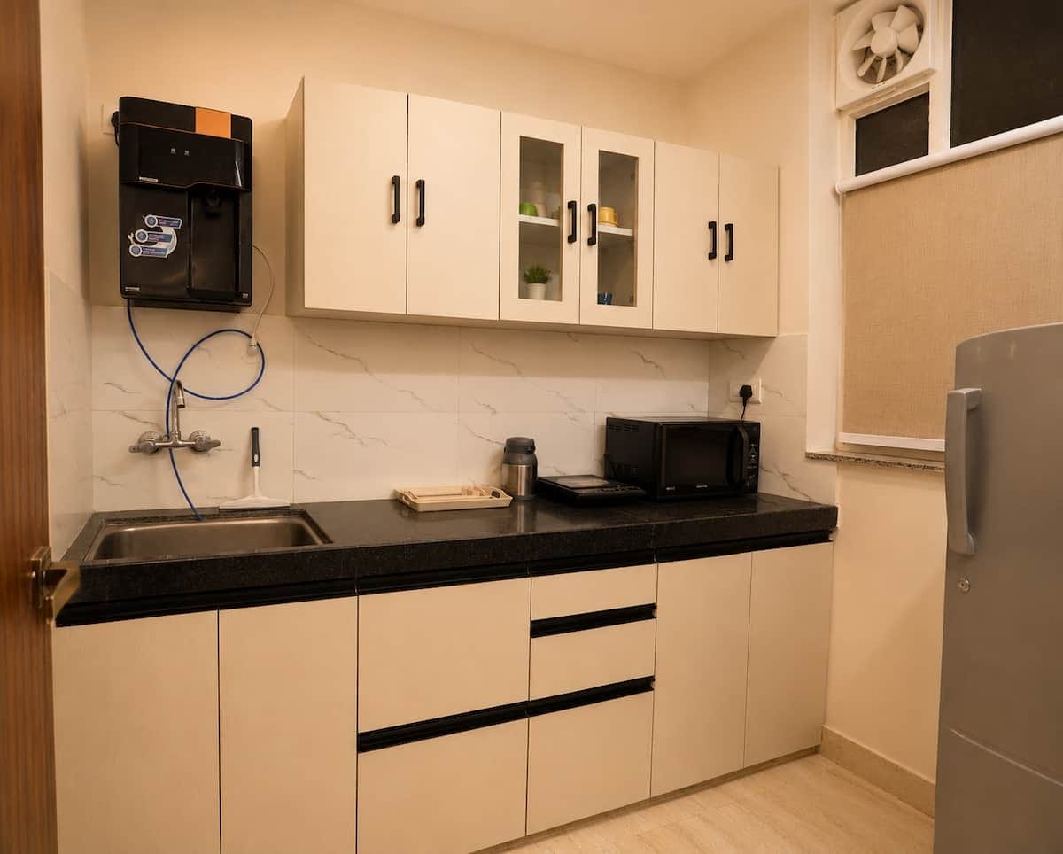 Kitchen with white cabinets, a black counter, microwave and chimney
