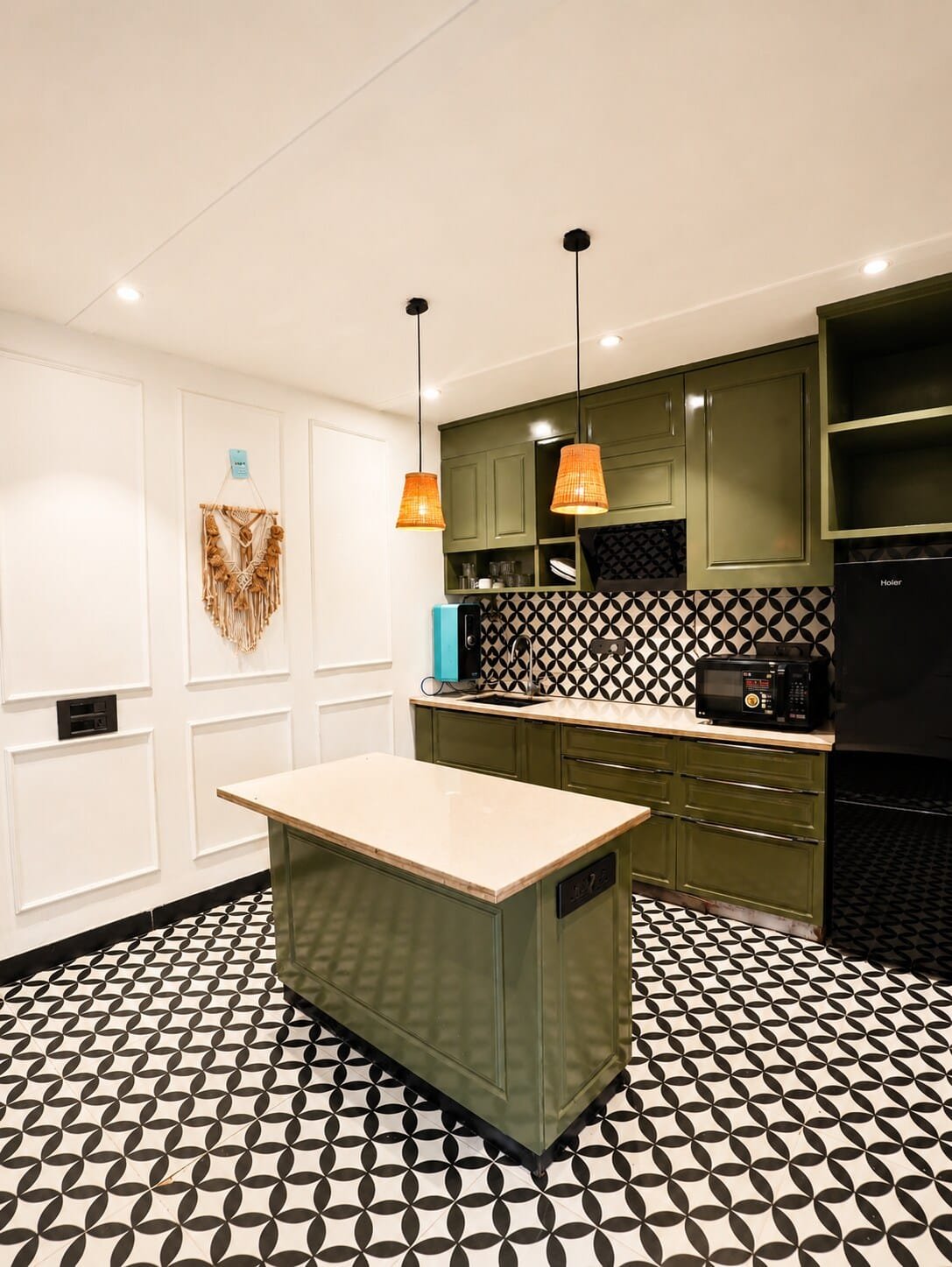 Kitchen with olive green cabinets, an island and pendant lights