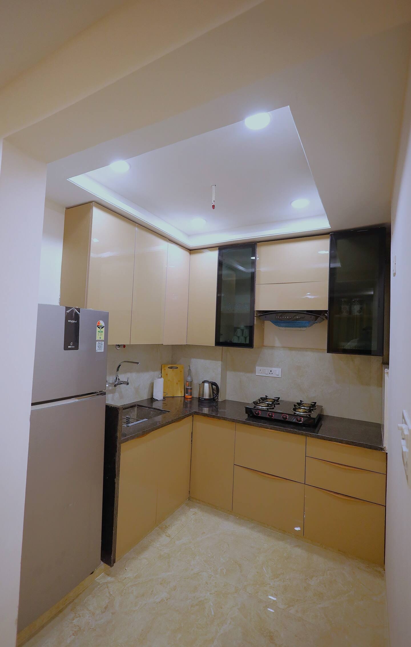 Compact kitchen with beige cabinets, a hob and a tall fridge