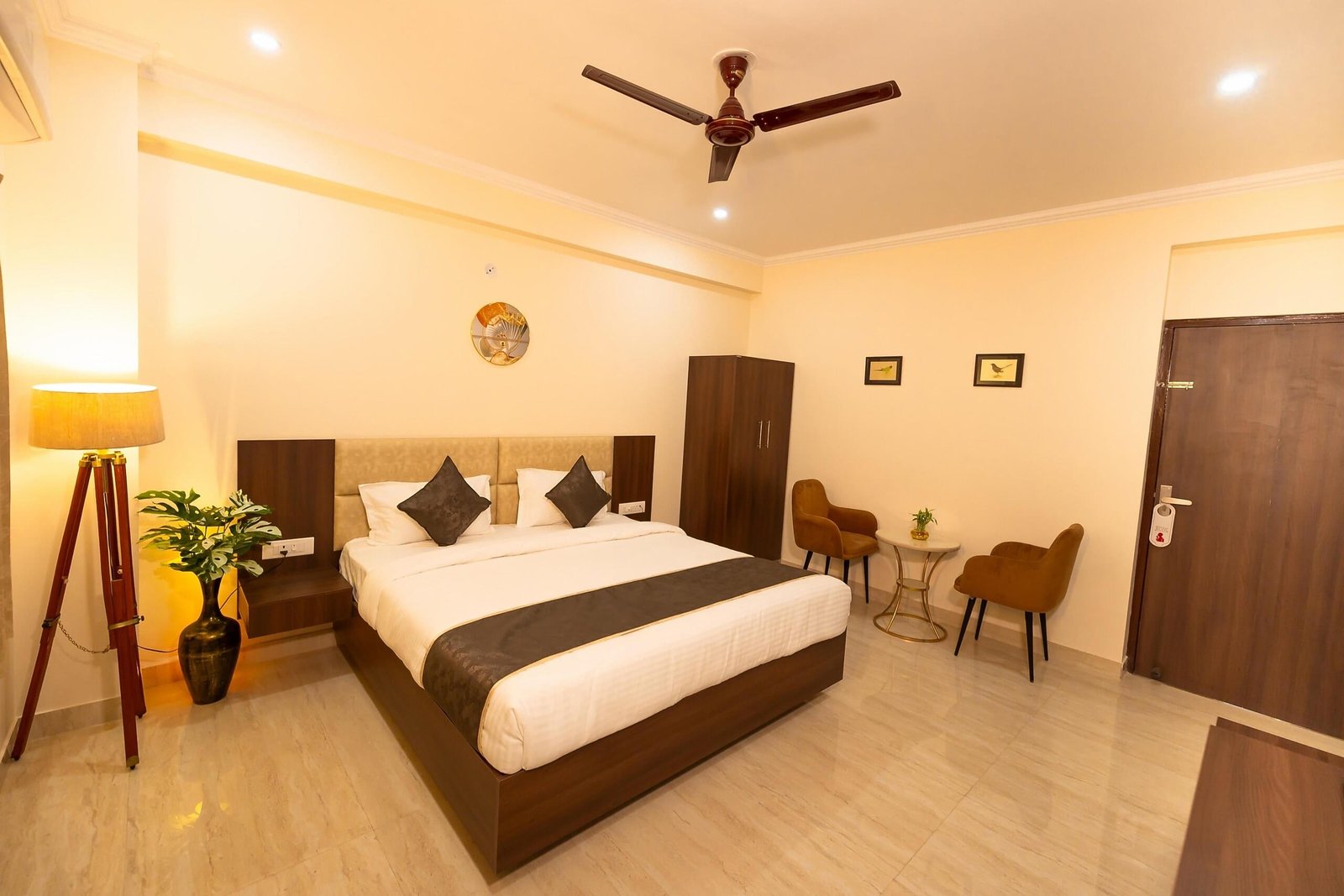 Guest room with a king bed, a tripod floor lamp and two armchairs by the door