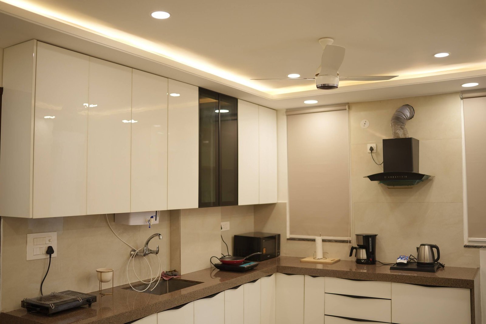 Kitchen counter with white cabinets, chimney hood, microwave and kettle