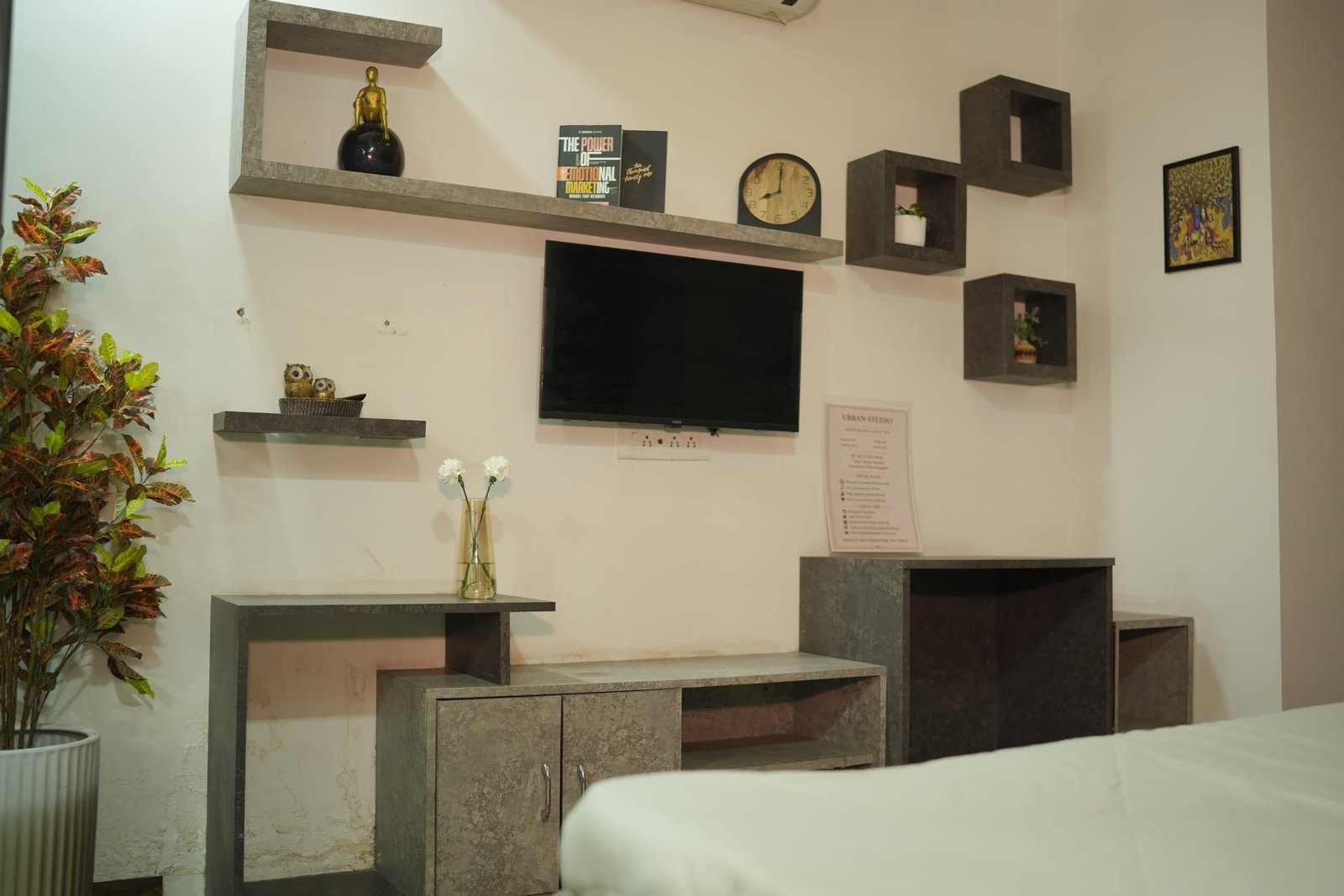 Desk and TV wall with floating shelves opposite the bed