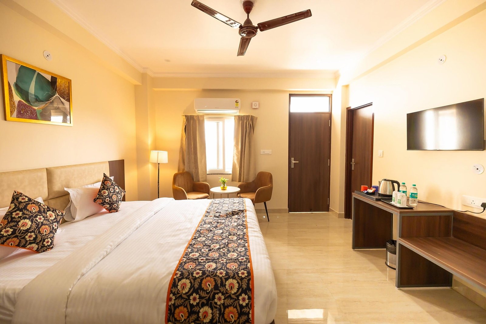 King bed with a patterned runner, with a desk and wall TV opposite