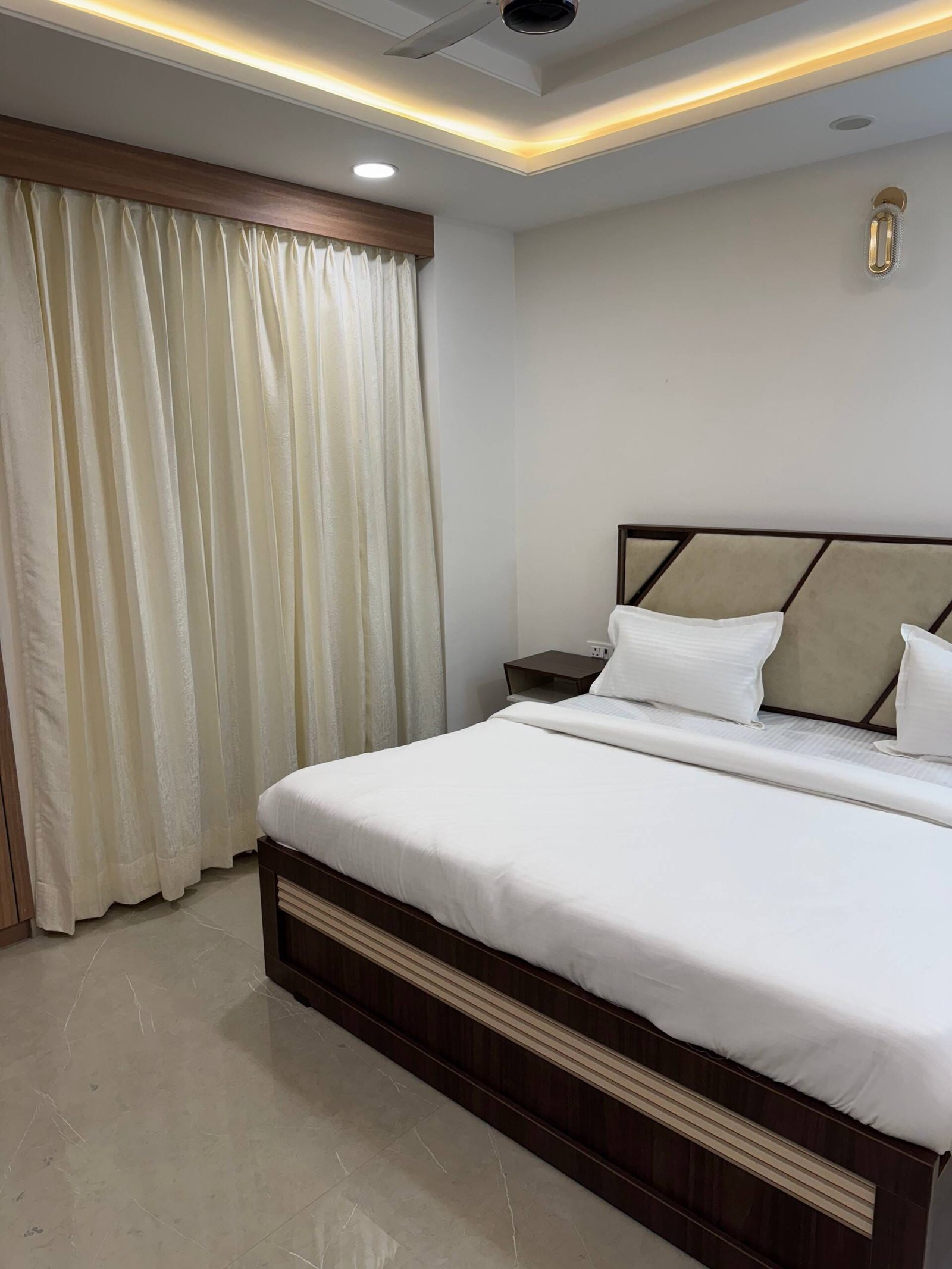 Bedroom 3 bed with a padded headboard beside full-length curtains