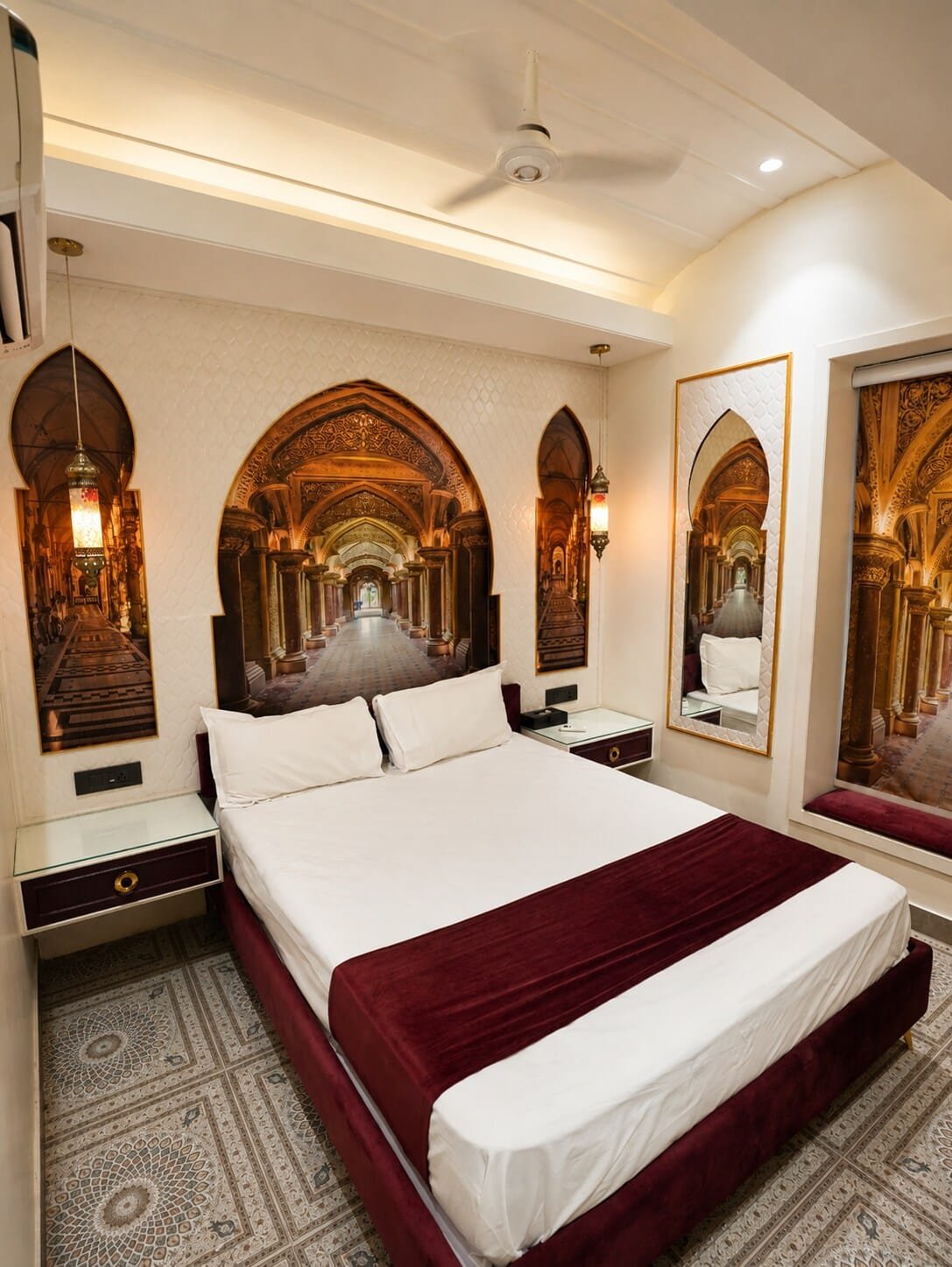 Bedroom with a maroon throw and a mural of an arched gallery