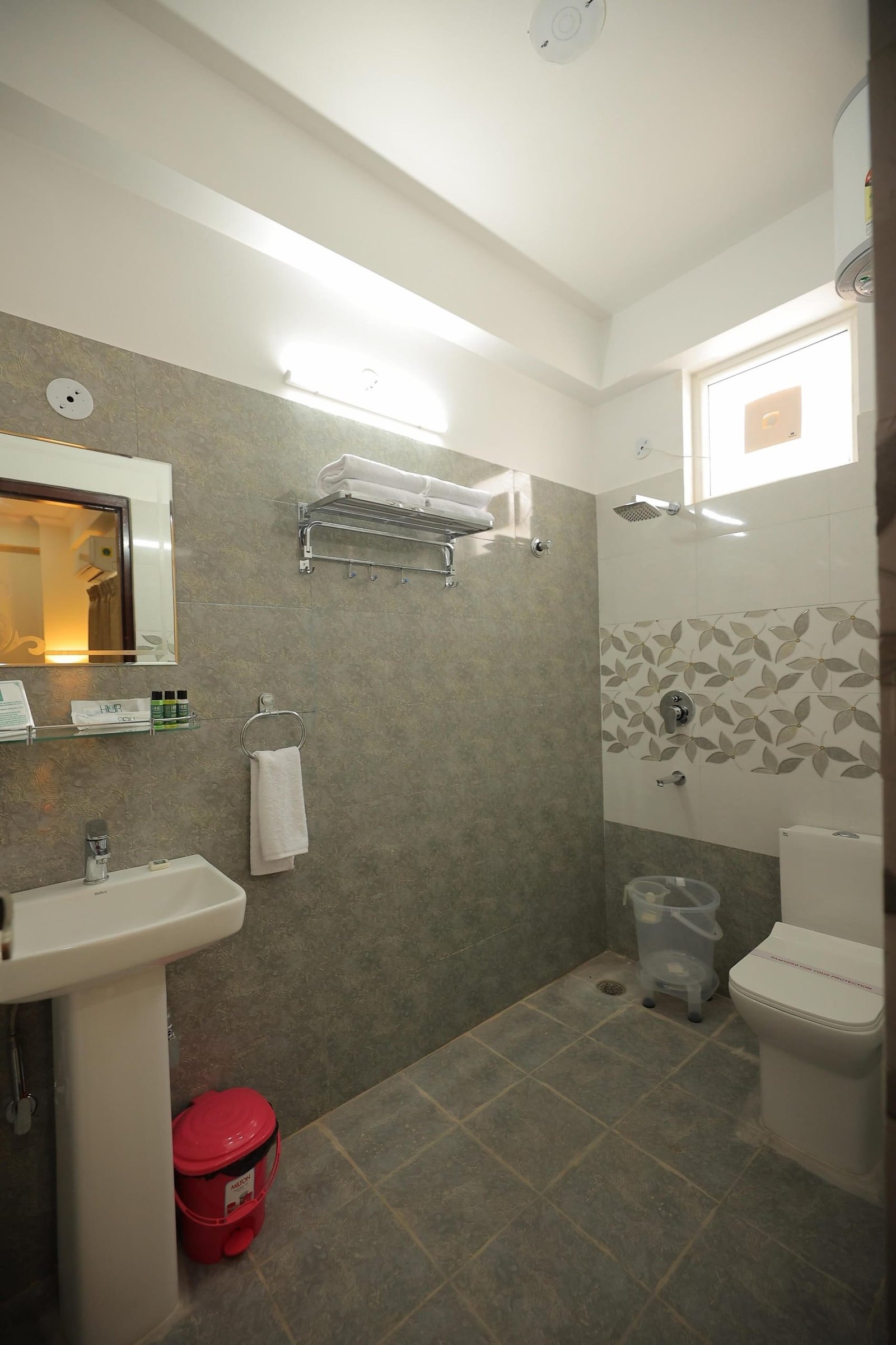 Bathroom with grey tiles, a pedestal basin, a towel rack and a shower