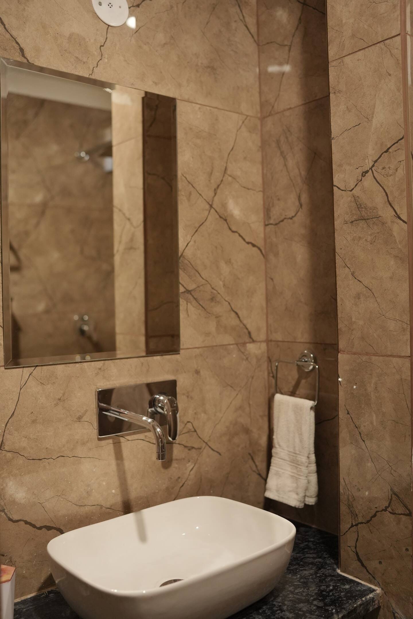 Bathroom with a vessel basin against marble-look stone tiles