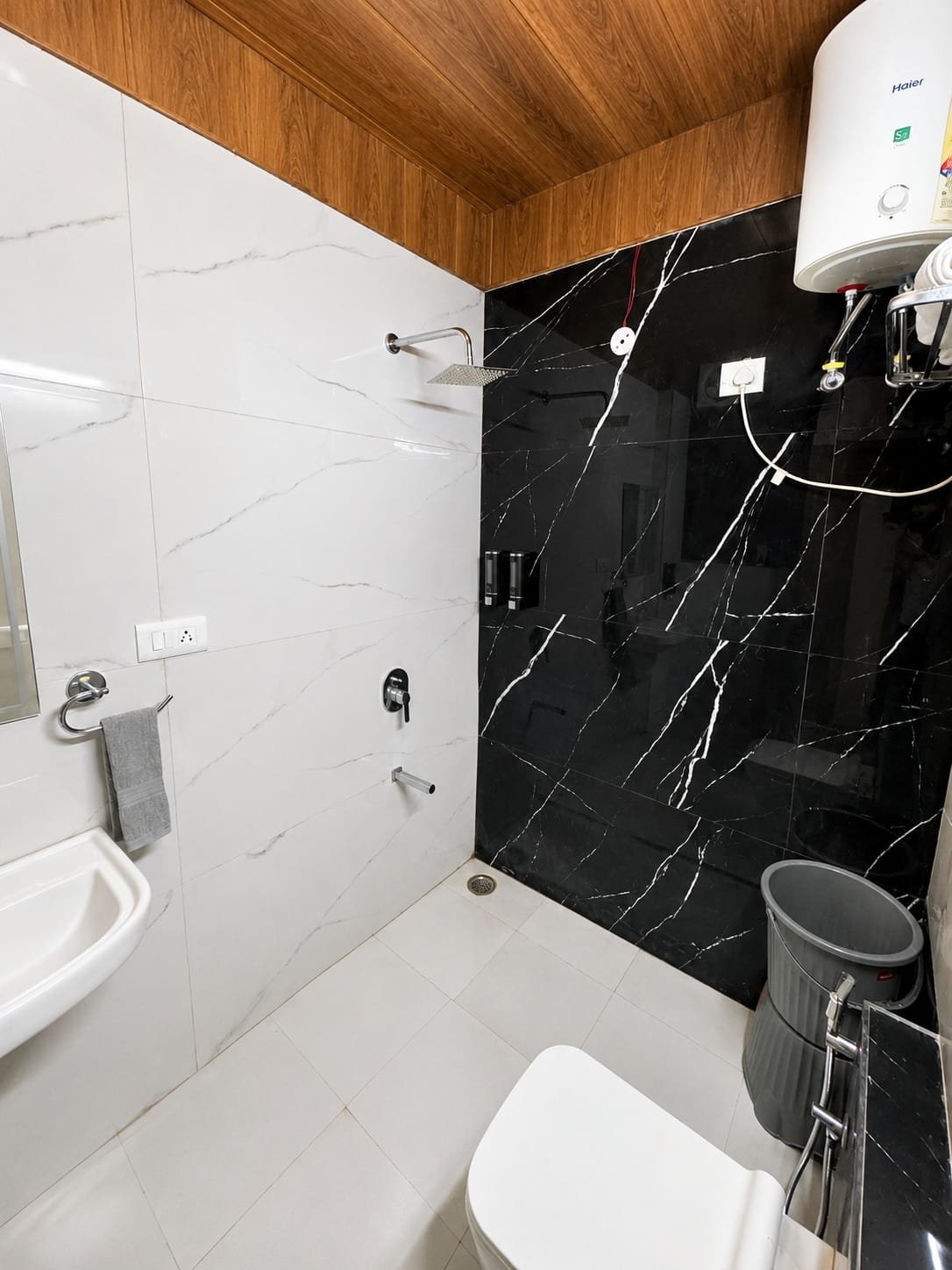Bathroom with black marble-look wall tiles and a water heater