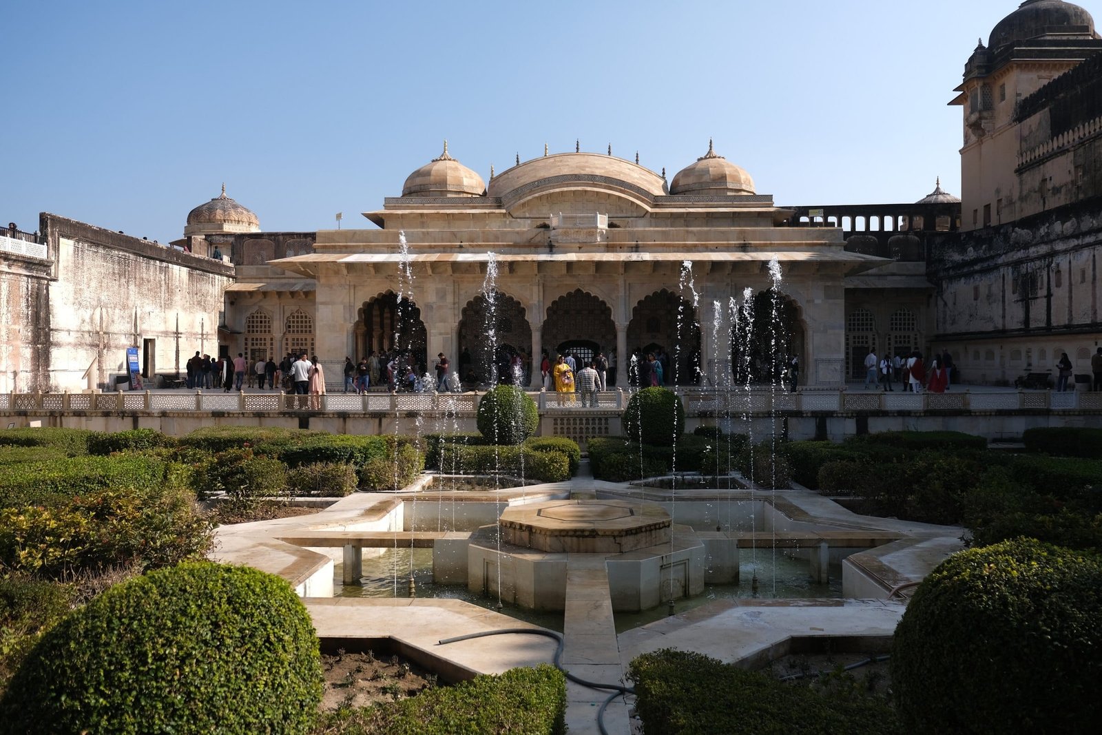 A courtyard garden at Amer Fort, arched halls and domed pavilions around it