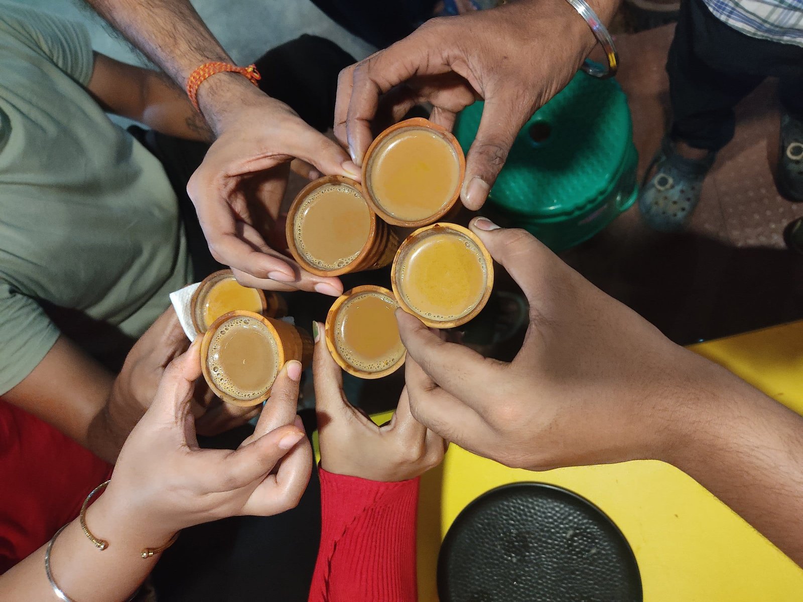Friends touching small glasses of chai together