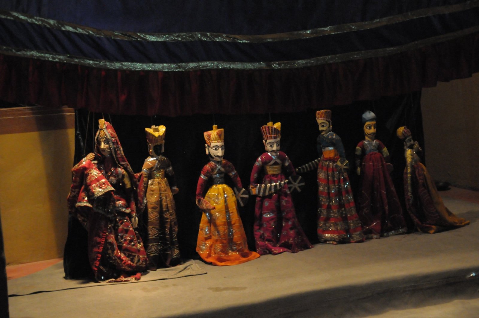 A row of kathputli string puppets in bright costumes on a stage